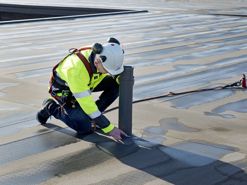 Řemeslník upravující rouru na střeše
